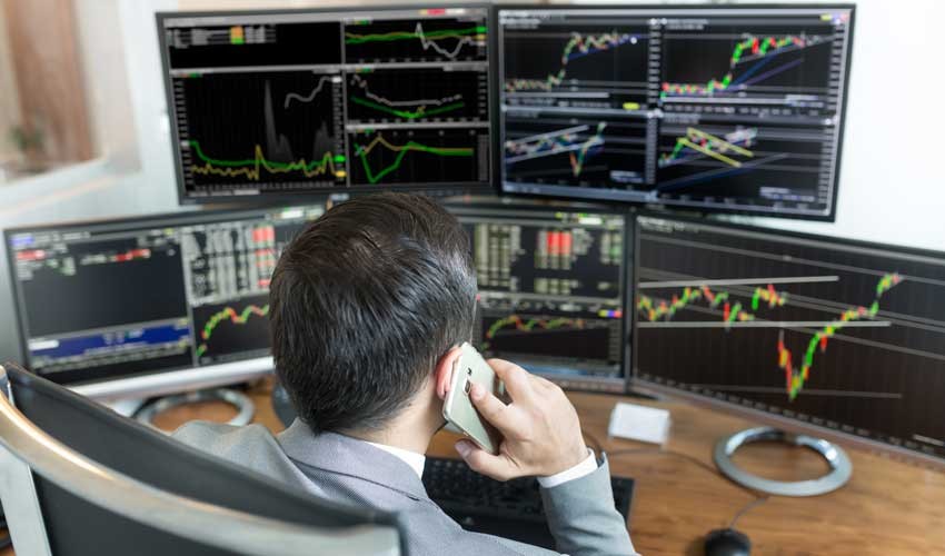 肩膀上方的股票经纪人在网上交易，用手机通话。